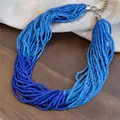 Makroansicht der mehrsträngigen Glasperlenkette in Blauverlauf auf Holzoberfläche - Mehrlagig Perlen / Blau