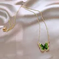 Elegant gold-tone butterfly necklace with green crystal inlay on satin fabric background - Zirconia Glass Butterfly Necklace / Gold