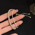 Close-up detail van een dubbellaagse zirkoon- en parelarmband met een verstelbare schuifregelaar - Dubbelgelaagd Kettingontwerp (HB4328)