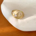Macro-opname van een goudkleurige geborstelde ring met zirkonia stermotieven - Ring - Goud