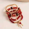 Primer plano detallado que muestra las texturas de un juego de pulseras de cuentas rojas y doradas - Set de 4 piezas / Rojo