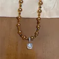 Exquisite Makroaufnahme einer braunen Perlenkette mit einem quadratischen Kristallanhänger - Braun