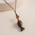 Detailed close-up of ethnic style wooden fish pendant with flower bead on woven rope necklace - Geometric Fish Style / Dark Coffee