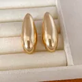 Detailed macro view of polished gold oval stud earrings resting on a soft cream jewelry tray - Earrings (HE35443) / Gold