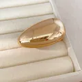 Close-up of golden smooth oval stud earring with high-shine metallic finish - Ring (HR3986) / Gold