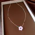 Detail van een kristallen bloemenketting met kleurrijke kralen op een zilveren ketting. - Roze