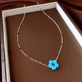 Gedetailleerde opname van kleurrijke kralenketting met een helderblauwe bloemhanger - Blauw