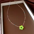 Detailopname van een zilveren kralenketting met veelkleurige accenten en een groene bloemhanger - Groen