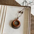 Primer plano de un collar con colgante de anillo de resina retro en bandeja beige. - Estilo de Disco de Doble Capa