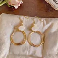 Elegante goldene konzentrische Creolen mit weißem Opal-Cabochon-Detail für modische Frauen - Orhaken - Gold - Weiß