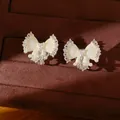 Gedetailleerde macro-opname van elegante strikoorbellen met emaille en parels - Oorclips / Wit