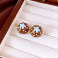 Gros plan de boucles d'oreilles marron à pois bleus et motif d'étoile dans un coffret - Or-Café-Bleu
