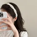Vista detallada de una elegante diadema ancha de tela blanca con lunares en el cabello - Blanco
