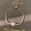 Gros plan d'un bracelet main de Fatma en or rose avec œil bleu et zircons brillants - Style Main de Fatma (HB7026)