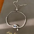 Vue détaillée d'un bracelet œil porte-bonheur argenté avec zircon bleu et breloque goutte - Style Oeil Larme (HB7025)