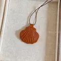 Detailopname van een bruine lederen schelphanger ketting met een dun bruin koordje. - Bruin