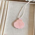 Detailopname van een roze schelpvormige lederen hanger ketting in een sieradenbakje. - Roze