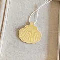 Detail van de geel leren schelphanger met wit koord op een getextureerde achtergrond - Geel