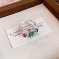 Nahaufnahme eines transparenten Harzrings mit bunten, funkelnden Strasssteinen-Detail. - Runder Schuppenring / Weiß-Grün