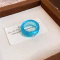 Detaillierte Makroansicht eines blauen Harzrings mit einem rosa Kristallakzent. - Runder Schuppenring / Blau