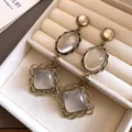 Gros plan de boucles d'oreilles vintage en or antique avec pierres claires dans un écrin. - Épissage de Couleurs Géométriques Ovale Losange / Tige en Argent-Or-Blanc