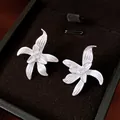 Nahaufnahme von silbernen Blumenohrringen mit Textur und Zirkonia in einer Schmuckschatulle - Silber-Ohrstecker-Stil / Silberweiß