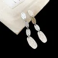 Vue rapprochée des boucles d'oreilles argentées avec des disques ovales au fini martelé - Clous à Franges Ovales Plissés (HE35501) / Argent