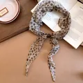 Détail d'un foulard en soie vintage à motif léopard avec une perle brune élégante. - Léopard Vintage