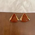 Vista detallada de aretes triangulares de gota de aceite con elegantes bordes dorados - Triángulo Dorado / Marrón
