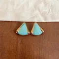 Primer plano de pendientes triangulares turquesa con borde metálico dorado - Triángulo Dorado / Azul