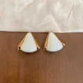 Primer plano detallado de elegantes pendientes triangulares de goteo blanco y dorado - Triángulo Dorado / Blanco