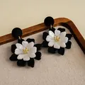 Detalle de pendientes de flores de acrílico blanco y negro de doble capa con centro dorado. - Estilo de Flor de Doble Capa (HE35423) / Contraste Blanco y Negro (HE35423)