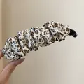 Close-up van een vintage bananenklem met geplooide bloemenprint in bruin en blauw - Twist Clip / Beige Koffie Bloemen