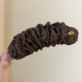 Detailopname van een luipaardprint bananenklem met een handgemaakt gouden label detail - Twist Clip / Donker Koffie