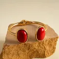 Nahaufnahme eines goldenen Armreifs im Retro-Stil mit ovalen roten Kunstharzsteinen. - Gold-Rot