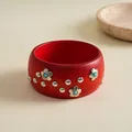 Nahaufnahme eines roten Holzarmreifs mit silbernen Blütennieten im Vintage-Stil - Red Painted Flower Bangle