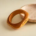 Detail eines runden Retro-Harzarmbands mit goldenen Nieten und schöner Holzmaserung. - Beige-Gold-Rund