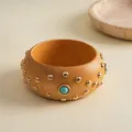 Nahaufnahme eines Vintage-Holzarmreifens mit goldenen Nieten und Türkisstein-Inlays. - Ethnic Turquoise Decor Bangle