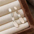 Elegantes pendientes ovalados de plata martillada en un joyero de terciopelo beige - Plateado