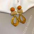Detailed view of vintage geometric acrylic earrings featuring amber resin pendants - Three-Stage Geometric Drop Style (HE35635) / Brown