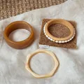 Detailansicht eines unregelmäßigen geometrischen Harz- und Holzarmband-Sets auf Leinenstoff - Bernstein und Marmor Geometrischer Stil