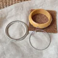 Nahaufnahme des dreiteiligen minimalistischen Armbandsets mit Holzmaserung und Silbertextur - Stern Holzmaserung Harz und Silberner Flechtseil Stil