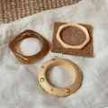 Detailansicht von drei minimalistischen Armreifen aus Harz und Holz mit Goldnieten - Bernstein Unregelmäßiges Quadrat und Holz-Nieten Stil