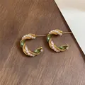 Gedetailleerde macro-opname van vintage gouden C-oorbellen met groen email en witte parels - C-Vormige Parel Emaille (Zilveren Stift)