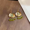 Close-up van vintage gouden oorbellen met groene kralenkwastjes in etnische stijl - Vintage Rond Kwastje (Oorhaken)