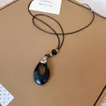 Gros plan d'un collier à pendentif en forme de goutte d'eau noire de style coréen. - Argent-Noir