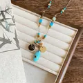 Gros plan d'un collier de perles bohème avec pendentif turquoise et breloque en or - Bleu