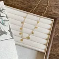 Détail d'un collier chaîne doré délicat avec de nombreuses petites médailles rondes suspendues - Or