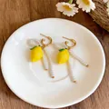 Detailed view of yellow lemon earrings with pearl accents on a white decorative plate - Stud Earrings / Silver / Gold-White-Yellow
