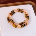 Gros plan d'un bracelet empilé en œil de tigre et perles de cristal ambré sur un plateau - Café-Verre (10mm)